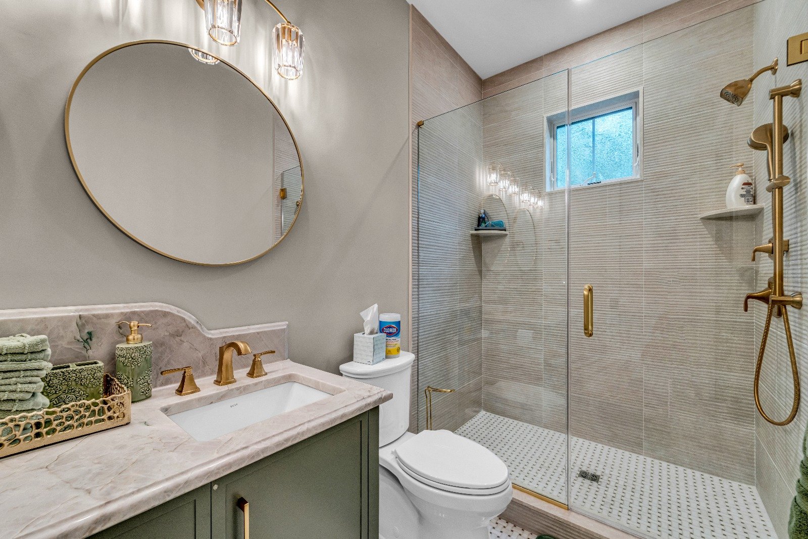 Modern bathroom remodel by Kitch Designs — walk-in shower, brass fixtures and round mirror